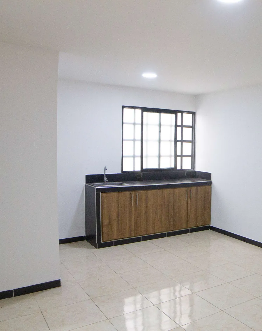 Cocineta sin muebles con mesón negro y ventana